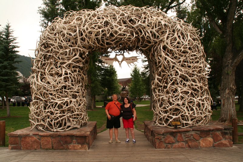 Trip (45).JPG - Ken and Sharon in front of one of the Antler Arches.  The four elk antler arches guarding the corners of Jackson Hole’s George Washington Memorial Park, more commonly called the Town Square, have become well known icons to the town’s many visitors. They’ve been featured in thousands of family photos over the years ours included.